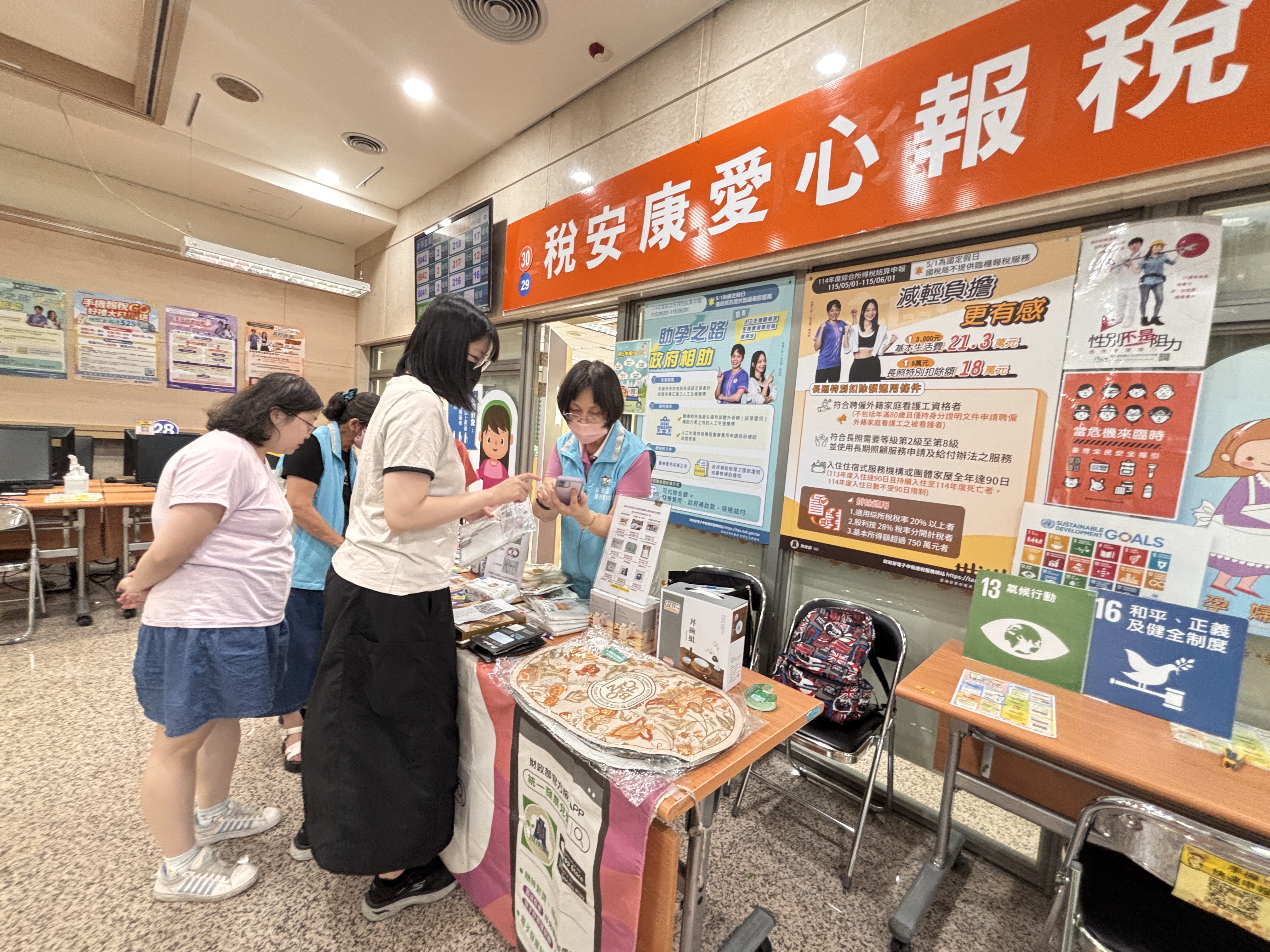 志工協助租稅宣導活動~服務民眾參加捐發票送愛心活動；張貼海報宣傳納稅者權利保護法、性別平等及全民安全指引等訊息。